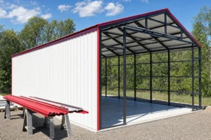 Metal carport partway through enclosure, one side sheeted with wall panels and the other side still open frame