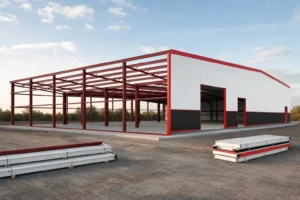 Partially erected steel building with exposed red iron frame on one half and finished white panels on the other