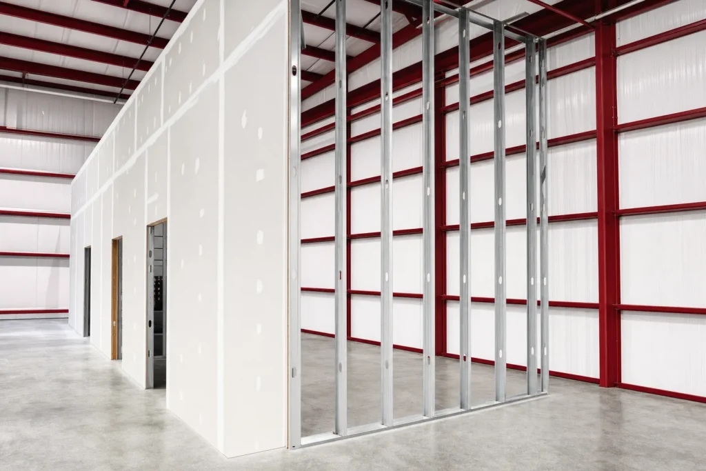 Framed and drywalled interior partition under construction inside a metal building