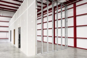 Framed and drywalled interior partition under construction inside a metal building