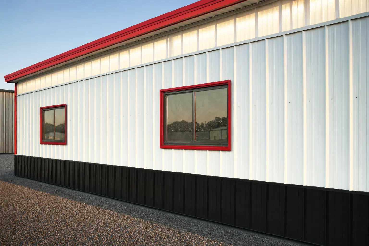 White metal building with framed windows and translucent skylight panels in the roof
