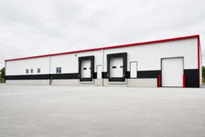 A long commercial metal warehouse shell with loading dock doors and a concrete truck apron
