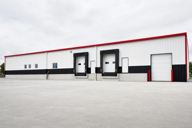 A long commercial metal warehouse shell with loading dock doors and a concrete truck apron