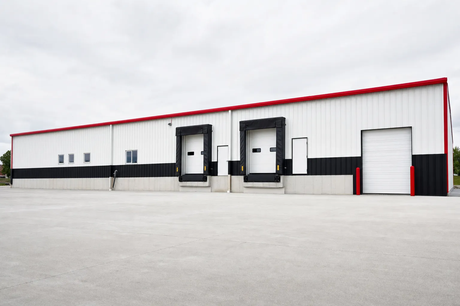 A long commercial metal warehouse shell with loading dock doors and a concrete truck apron