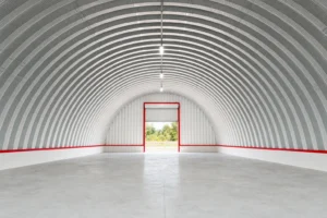 Interior of an empty steel quonset hut looking down the arch toward an end wall roll-up door
