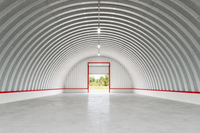 Interior of an empty steel quonset hut looking down the arch toward an end wall roll-up door